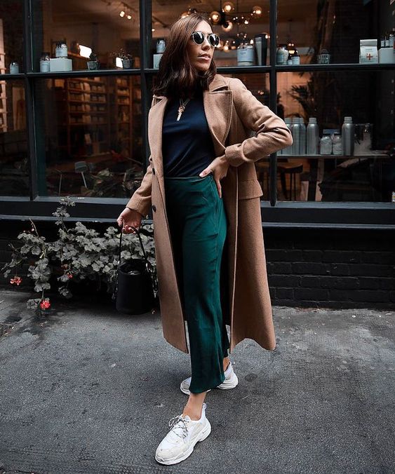 a navy turtleneck, emerald cropped pants, white trainers and a camel midi coat compose a lovely and comfy look