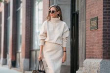 a neutral turtleneck sweater and a matching pencil midi skirt, cognac wide boots and a large printed bag