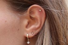 a silver hoop earring with a tiny star pendant and matching star studs all over the ear