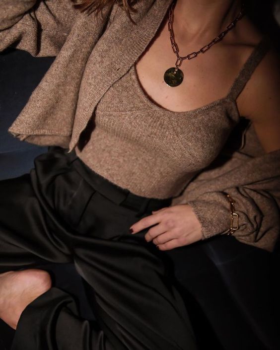 a stylish and chic outfit of black pants, a brown knit top and cardigan, a chain necklace and a matching bracelet