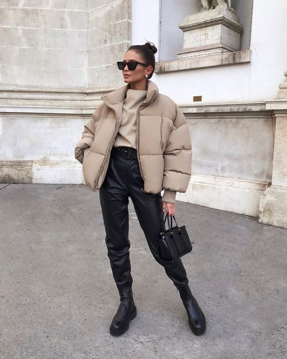 a stylish and laconic look with a tan top, black leather pants, black Chelsea boots and a black bag plus a tan cropped puffer jacket