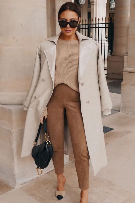 a stylish and simple outfit with a tan sweater, suede brown pants, two tone shoes and a black bag plus a neutral coat