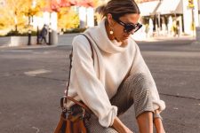 a stylish and simple outfit with an oversized white sweater, plaid pants, white hiking boots and an amber bag