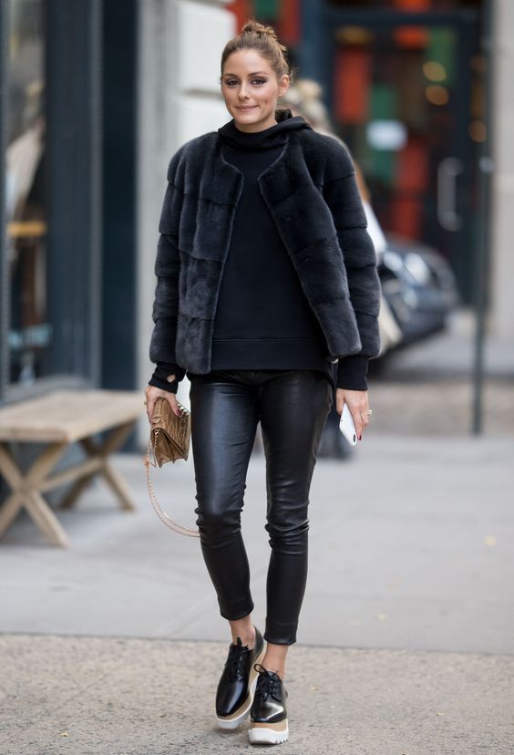 a total black look with leather leggings, boots, a hoodie and a faux fur jacket plus a tan bag