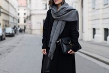 a total black outfit with leather pants, trainers, a coat, a beanie, a bag and an oversized grey scarf