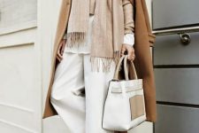 a white shirt, a tan sweater, white pants, tan suede shoes, a tan striped scarf, a camel coat and a white bag