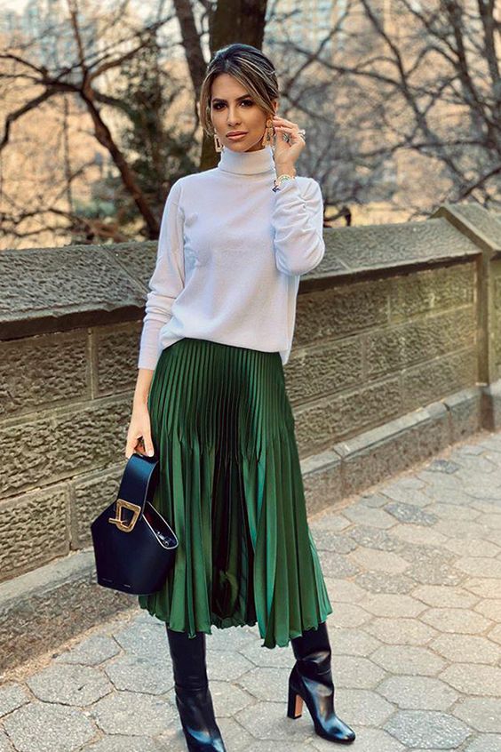 a white turtleneck, a green metallic pleated midi, black boots and a black bucket bag for a feminine feel