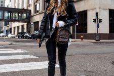 a white turtleneck sweater, black leather leggings, boots, a black shearling coat and a brown backpack