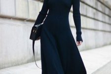 an elegant black A-line midi sweater dress, black booties, a black bag and statement earrings