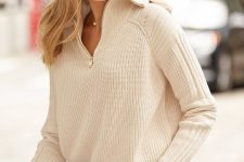 an ivory chunky knit zip sweater and light blue jeans for a chic and trendy look