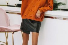 an orange oversized sweater, a black leather asymmetrical mini skirt, ivory sock boots and an ivory beret