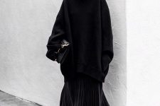an oversized black sweater, a black pleated midi and sock boots plus a large black bag