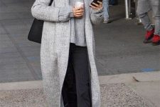 an oversized grey sweater, black striped pants, black boots, a grey midi coat and a black bag