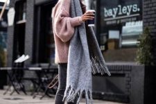 an oversized pink sweater, grey jeans, black booties, an oversized grey scarf for a cozy winter look