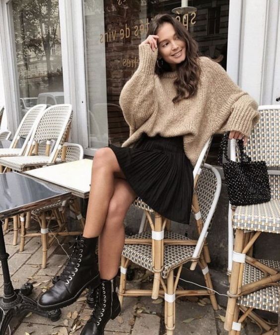 an oversized tan sweater, a black pleated mini, black combat boots and a beaded bag is amazing and chic