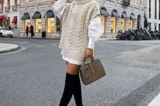 an oversized white shirt, an ivory sweater, a tan bag and black tall suede boots for a feminine look