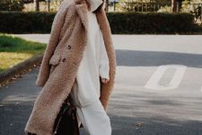 an oversized white sweater, white cropped pants, tan shoes, a brown fuzzy coat and a large black bag for work