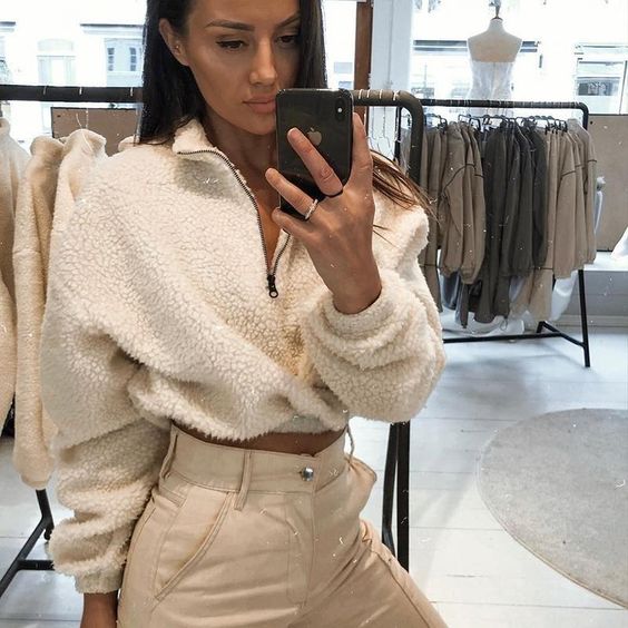tan high waisted pants and a white fuzzy zip sweater that is cropped for a sexy feel