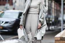 With gray turtleneck, gray loose pants, white clutch and gray coat