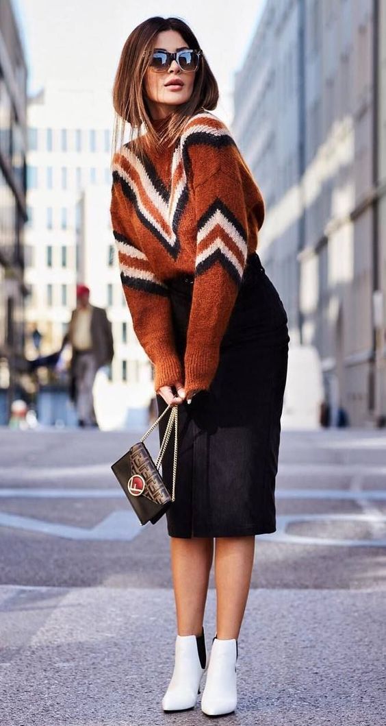 a bold geometric print sweater with a high neckline, a black pencil midi, white ankle booties and a black bag for a chic look