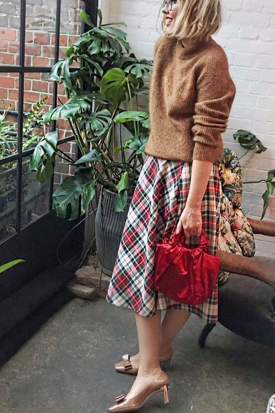 a brown sweater, a bold plaid pleated midi, vintage brown shoes and a red bag for pulling off a vintage holiday look