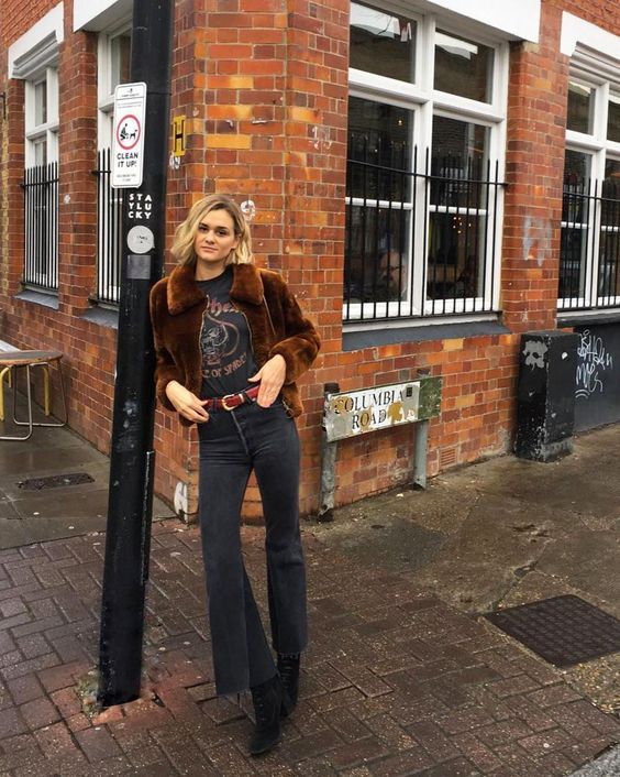 a dark winter outfit with a printed tee, black flare jeans, black suede boots, a brown faux fur jacket