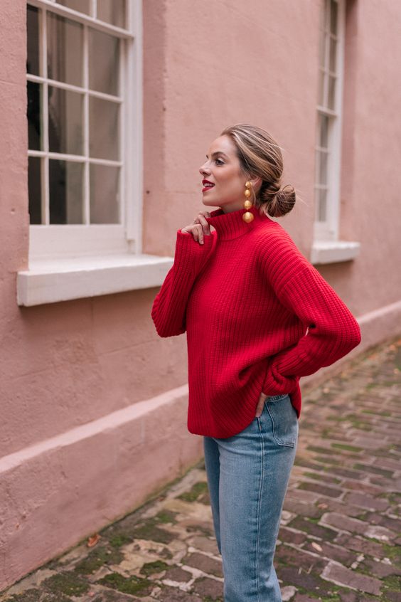 a red turtleneck sweater, blue skinnies and statement earrings for a chic and bold holiday look