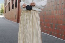 a simple and chic outfit with a white sweater, a gold pleated midi, snakeskin boots and a tiny black bag