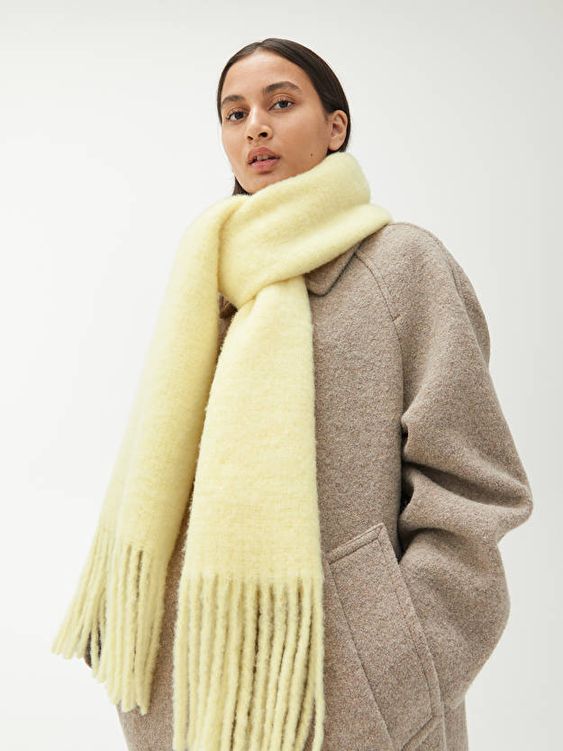 a tan coat with a lemon yellow scarf with long fringe that will add color and catchiness to the look