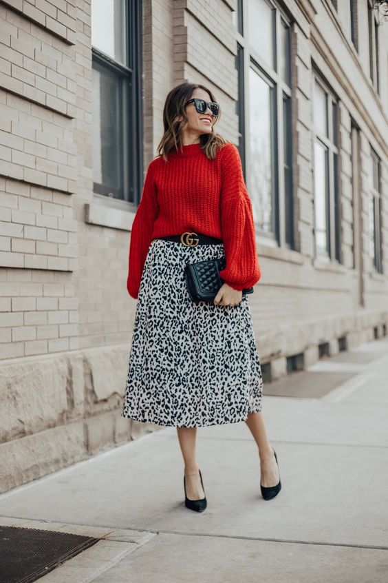a trendy holiday look with a red puff sleeve chunky sweater, a leopard print skirt, black shoes and a black clutch