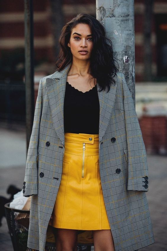 a black top with a scallop edge, a yellow leather mini skirt, a grey plaid coat