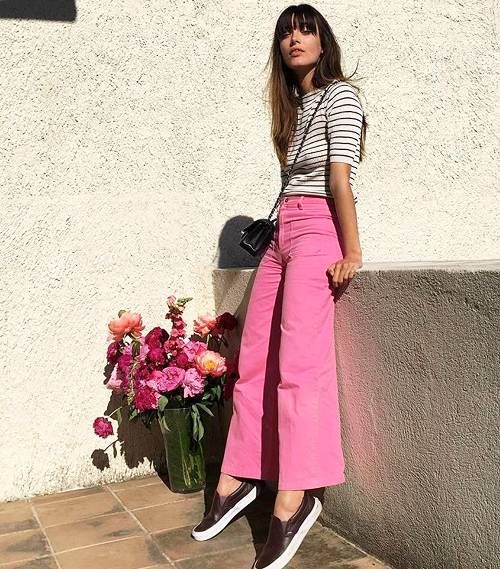a bold and chic look with a striped top, pink pants, black flipflops, a black bag compose an outfit with a Parisian feel