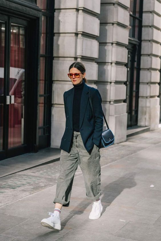 a black turtleneck, a navy oversized blazer, olive green shaggy jeans, white trainers and a black bag