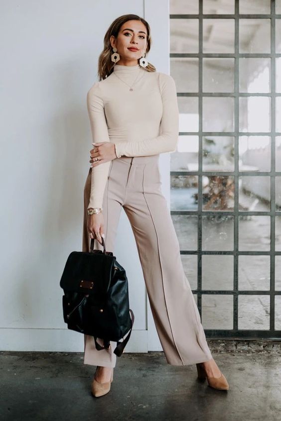 a neutral turtleneck, grey trousers, tan shoes, statement earrings and a black backpack for spring