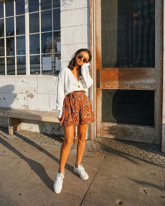 a white cardigan worn as a shirt, a colorful printed A line skirt, white sneakers for a cute date look