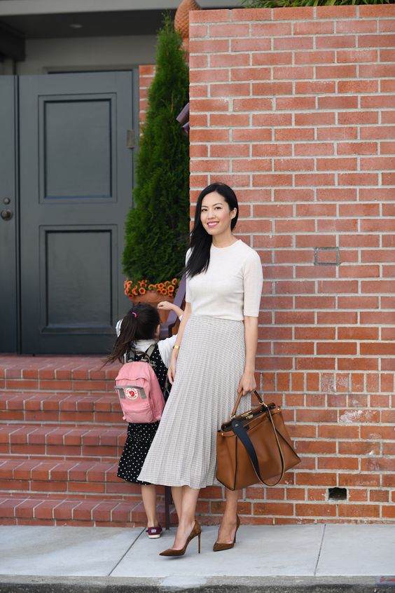 a white high neck top with short sleeves, a plaid pleated midi skirt, brown shoes and a brown tote