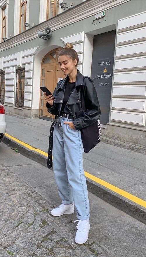 a black t-shirt, an oversized black leather jacket, blue mom jeans, white sneakers and a black tote