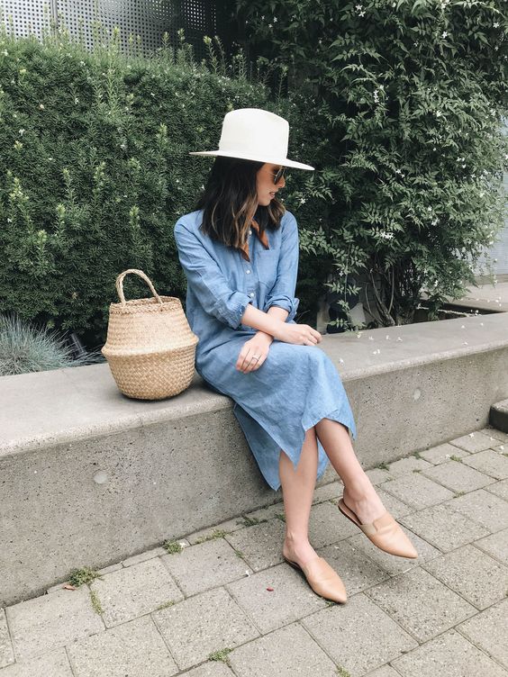 a blue linen midi shirtdress, nude mules, a bucket bag and a white hat for spring and summer