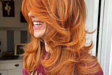 a copper voluminous butterfly haircut on long hair, with blonde highlights and curled ends is adorable