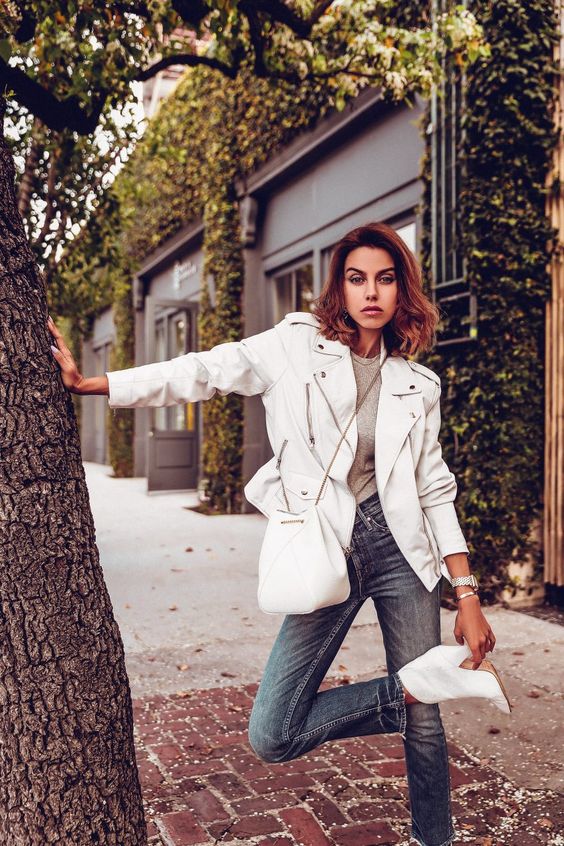 a grey t-shirt, a white leather jacket, blue jeans, white boots and a white bag