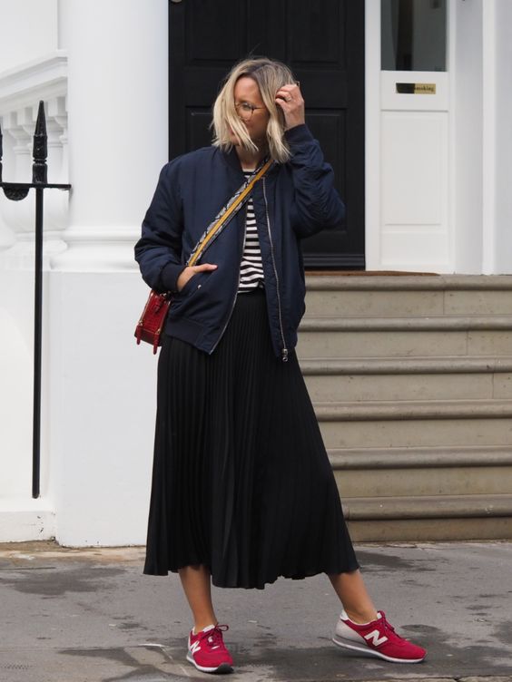 a striped tee, a black pleated midi, a navy bomber jacket, red trainers and a red bag
