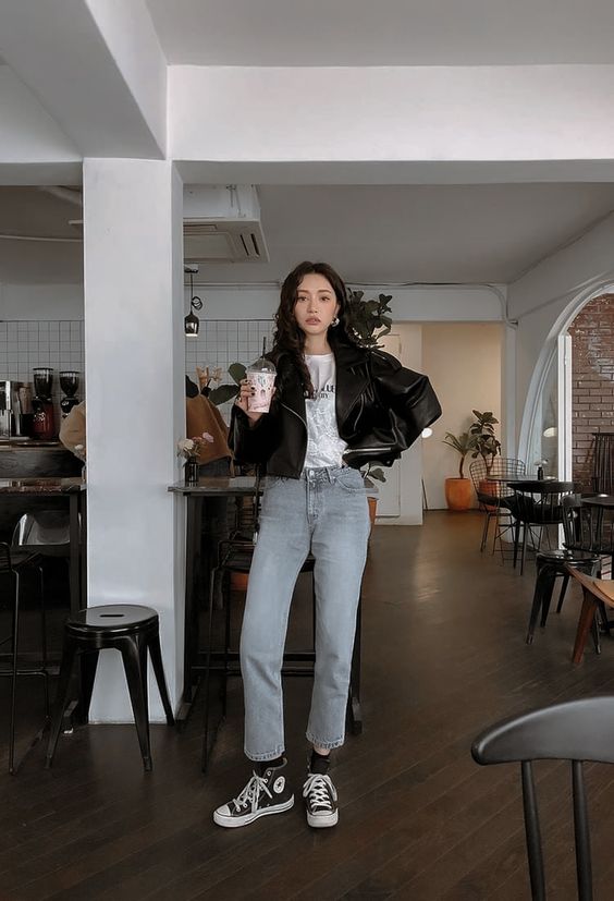 a white printed tee, a black leather jacket, light grey moms, black sneakers for a casual spring look