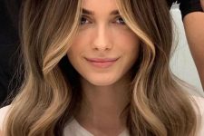 long brunette hair with blonde balayage and face-framing highlights, with volume and waves is a catchy and chic idea