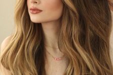long brunette hair with blonde face-framing highlights and balayage, volume and waves, is adorable