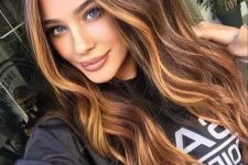 long dark brunette hair with golden blonde balayage and face-framing highlights plus waves looks cool