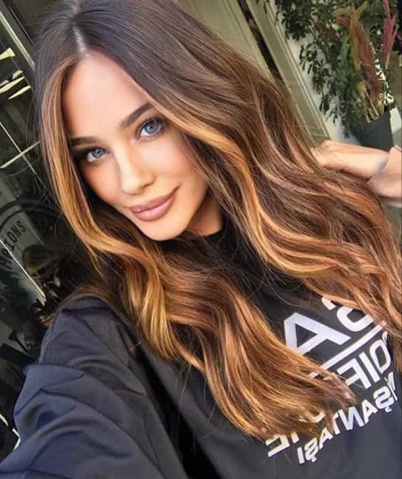 long dark brunette hair with golden blonde balayage and face-framing highlights plus waves looks cool