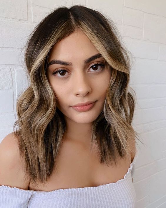 Medium length brunette hair with blonde balayage and face framing highlights plus waves is a catchy and cool idea