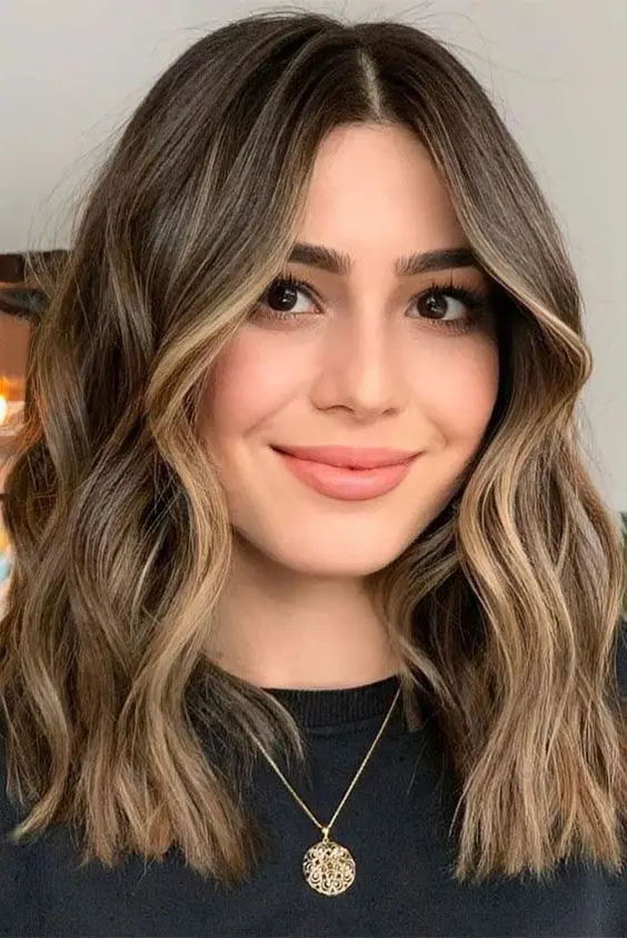 medium-length brunette hair with blonde highlights including face-framing ones and waves