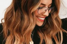 medium-length dark brunette hair with copper balayage and face-framing highlights and waves looks bold