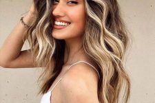 medium to long dark brunette hair with blonde balayage and face-framing highlights, with a lot of volume and waves